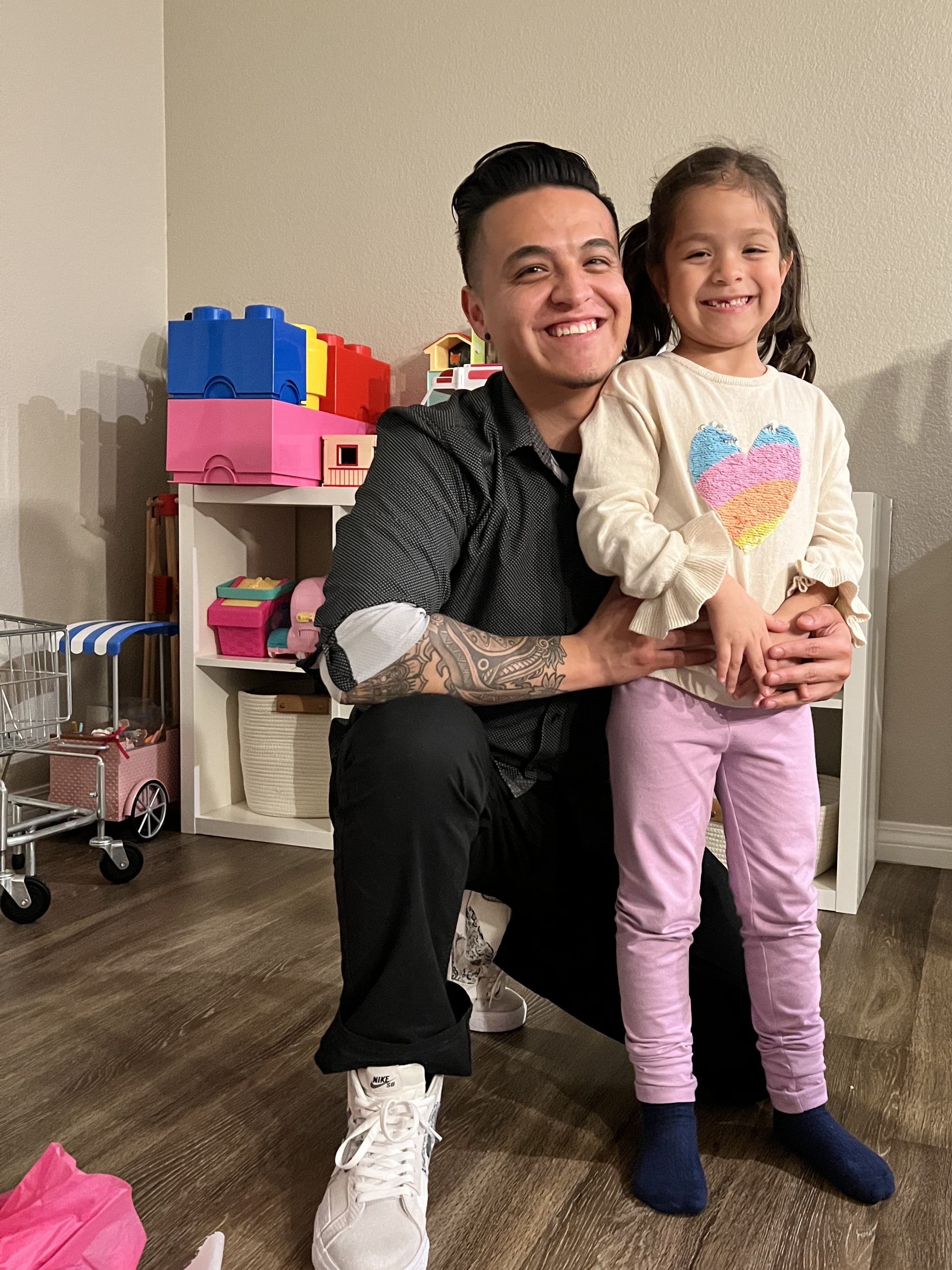 The founder kneeling beside his smiling daughter in their playroom